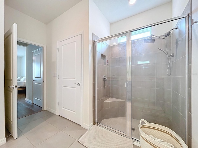 bathroom with a shower stall, tile patterned flooring, connected bathroom, and baseboards