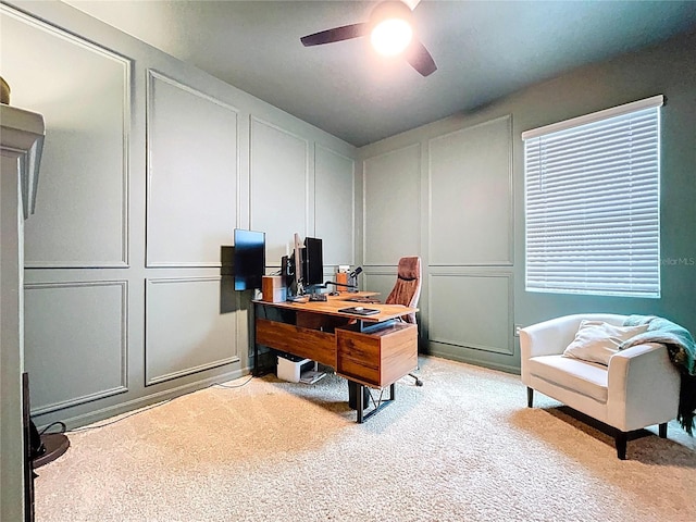 home office with a decorative wall, a ceiling fan, and light colored carpet