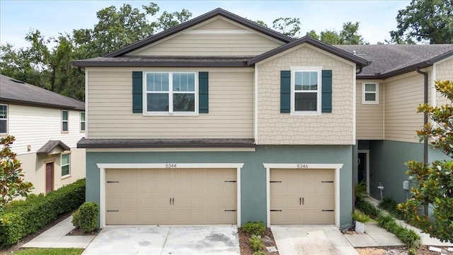 townhome / multi-family property featuring driveway, a garage, and stucco siding