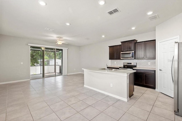kitchen with appliances with stainless steel finishes, a ceiling fan, backsplash, open floor plan, and light tile patterned floors