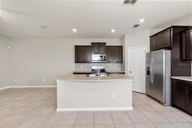 kitchen featuring stainless steel appliances, light tile patterned floors, a sink, tasteful backsplash, and light countertops