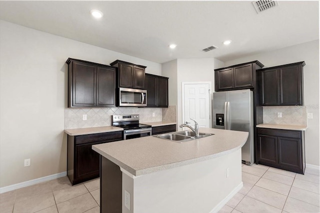 kitchen featuring appliances with stainless steel finishes, a sink, light tile patterned floors, tasteful backsplash, and light countertops