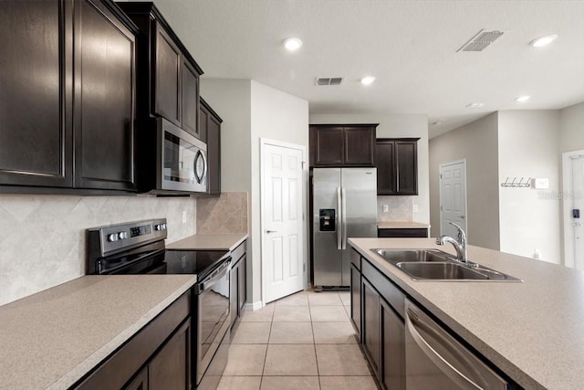 kitchen featuring stainless steel appliances, a sink, tasteful backsplash, light countertops, and light tile patterned floors