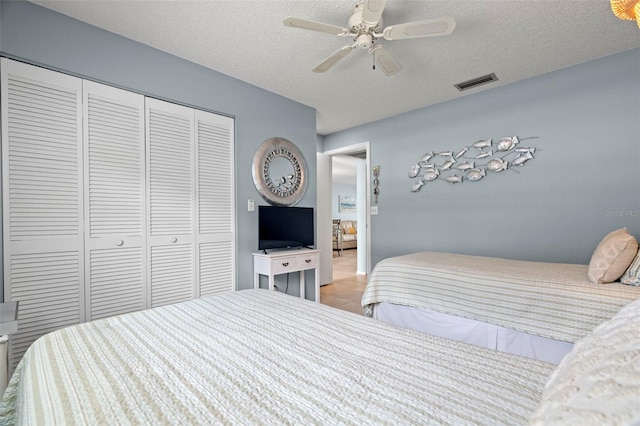 bedroom with a closet, a textured ceiling, light tile patterned floors, and ceiling fan