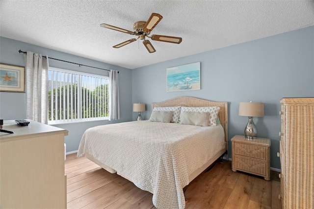 bedroom with wood finished floors, baseboards, ceiling fan, and a textured ceiling