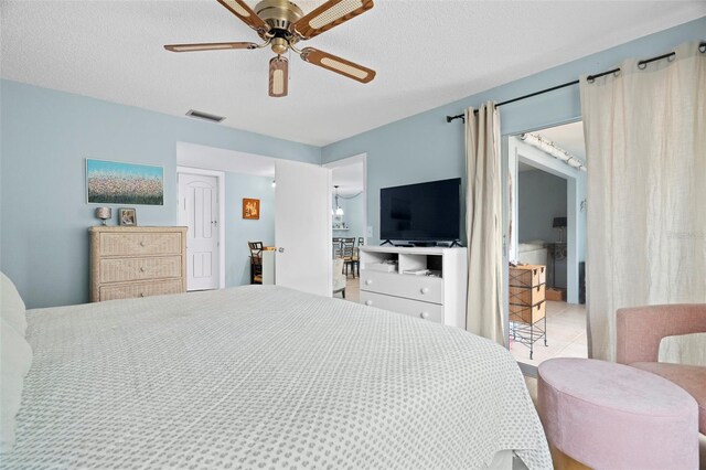 tiled bedroom featuring a ceiling fan and a textured ceiling
