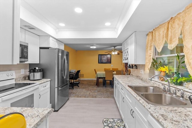 1453 62nd Ter S, Saint Petersburg, FL 33705 - kitchen featuring appliances with stainless steel finishes, a sink, ornamental molding, a tray ceiling, and white cabinetry