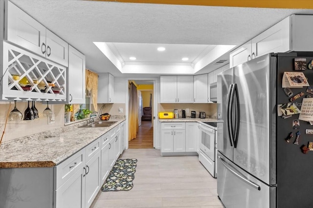 1453 62nd Ter S, Saint Petersburg, FL 33705 - kitchen with freestanding refrigerator, white electric stove, a sink, a tray ceiling, and light wood-style flooring