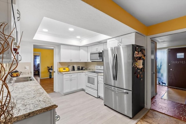1453 62nd Ter S, Saint Petersburg, FL 33705 - kitchen featuring stainless steel appliances, a tray ceiling, white cabinetry, light countertops, and recessed lighting