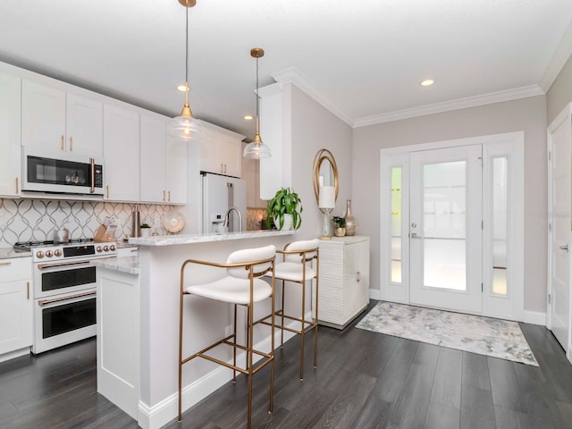 2807 W Hawthorne Rd Unit 11, Tampa, FL 33611 - kitchen featuring white appliances, dark wood finished floors, tasteful backsplash, white cabinetry, and crown molding