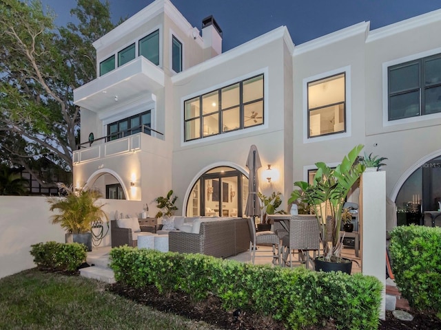 2807 W Hawthorne Rd Unit 11, Tampa, FL 33611 - back of house at twilight with an outdoor hangout area, stucco siding, a patio, and a balcony