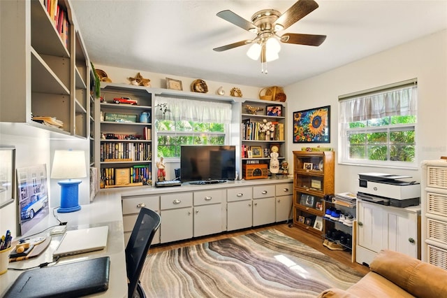 home office featuring plenty of natural light, a ceiling fan, and wood finished floors