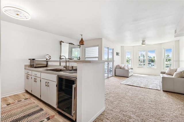 5712 Biscayne Ct Unit 103, New Port Richey, FL 34652 - kitchen with beverage cooler, open floor plan, a peninsula, a sink, and white cabinetry