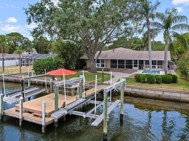 dock area featuring boat lift, a water view, an outdoor pool, and a lawn