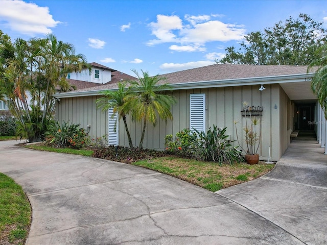 view of property exterior featuring a shingled roof, board and batten siding, and concrete driveway