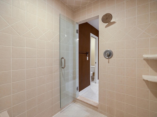 full bath featuring a tile shower, tile patterned flooring, toilet, and tile walls