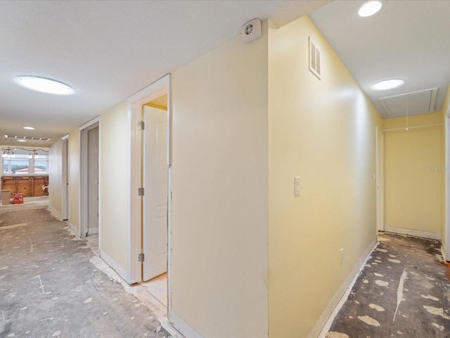 hallway with attic access and baseboards
