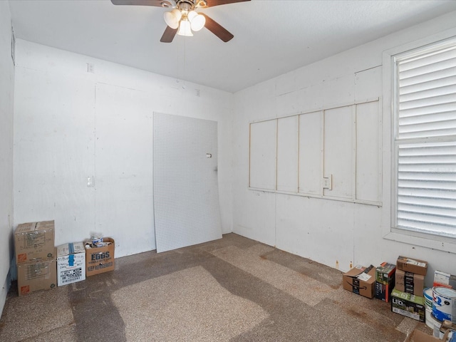 carpeted empty room with a ceiling fan