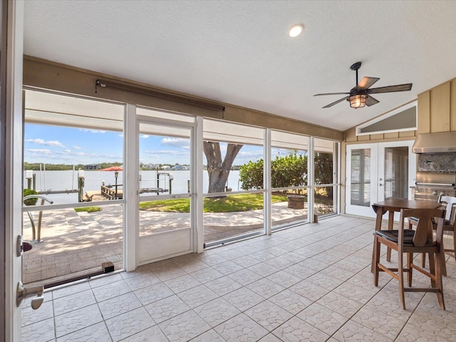sunroom / solarium featuring a water view, a ceiling fan, french doors, and lofted ceiling