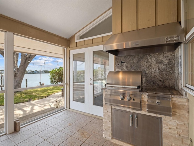 kitchen with lofted ceiling, a water view, french doors, under cabinet range hood, and a textured ceiling