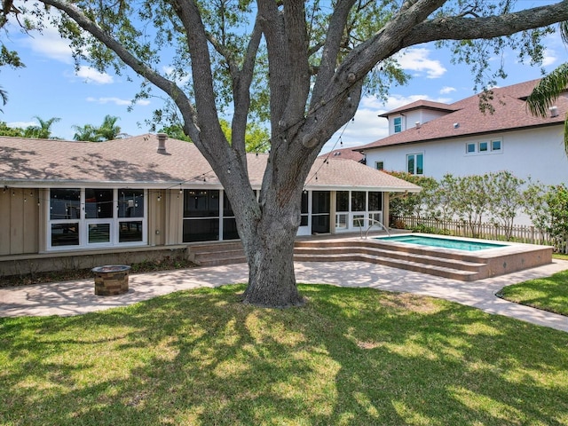 back of property with a sunroom, a patio, and a fire pit