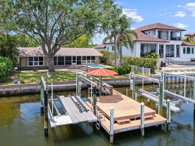 dock area with boat lift, a water view, and a patio