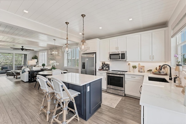 kitchen with appliances with stainless steel finishes, a sink, wooden ceiling, a center island, and a breakfast bar area