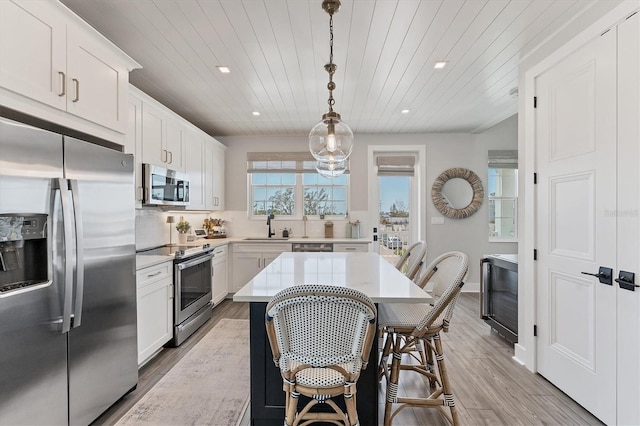 kitchen featuring stainless steel appliances, light countertops, wood ceiling, light wood-style flooring, and tasteful backsplash
