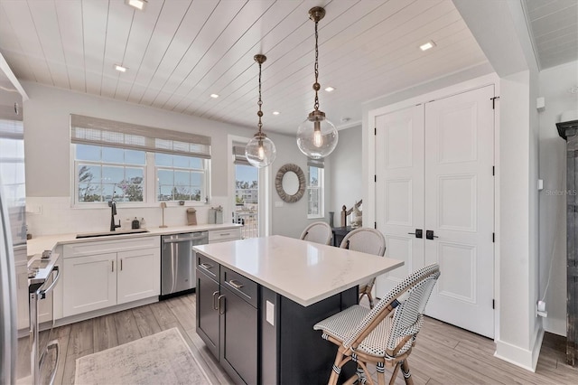 kitchen with a sink, stainless steel dishwasher, wood ceiling, a breakfast bar area, and range