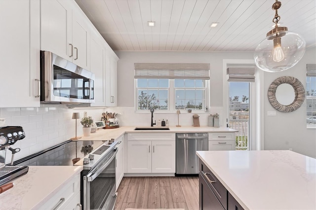 kitchen featuring appliances with stainless steel finishes, a sink, light wood-style floors, light countertops, and white cabinets