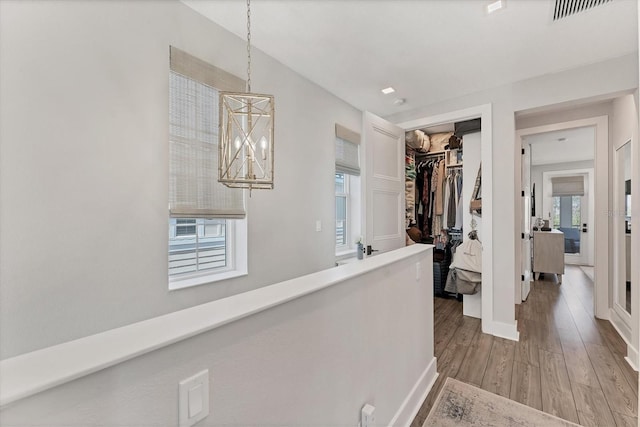 hall with wood finished floors, baseboards, and a chandelier