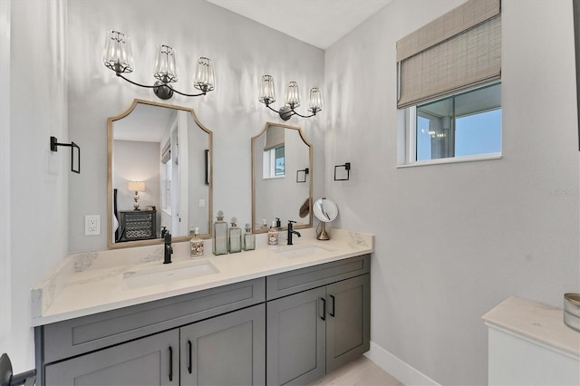full bathroom with double vanity, baseboards, and a chandelier