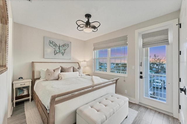 bedroom featuring access to exterior, light wood-style flooring, and baseboards