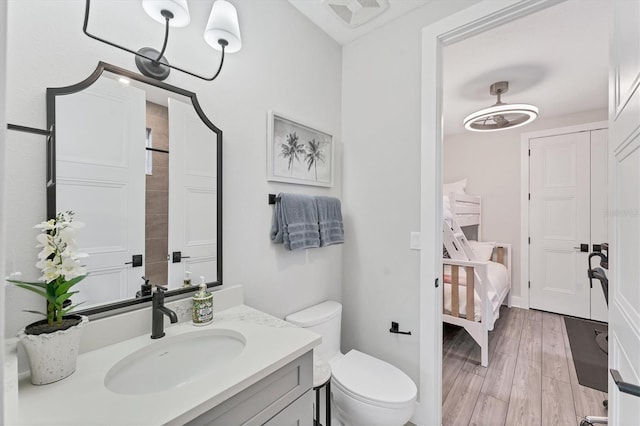 ensuite bathroom with toilet, wood finished floors, and vanity