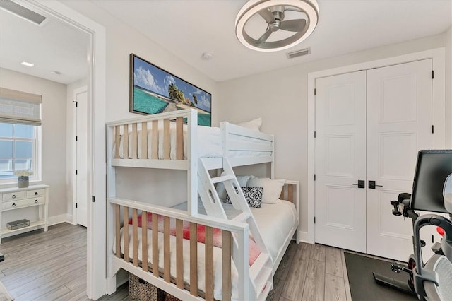 bedroom with wood finished floors, a closet, and baseboards