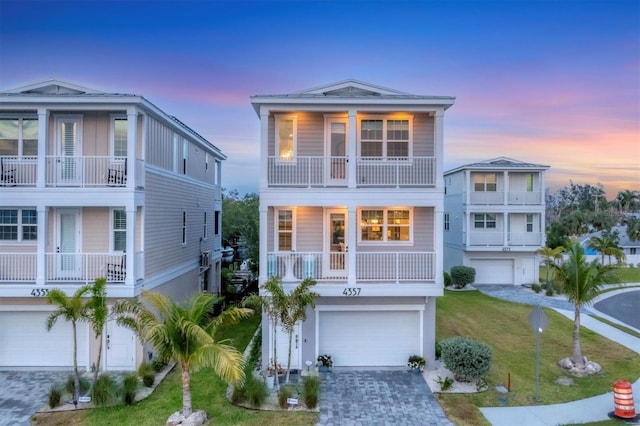4357 Marina View Way, Cortez, FL 34215 - raised beach house with an attached garage, decorative driveway, a balcony, and a front yard