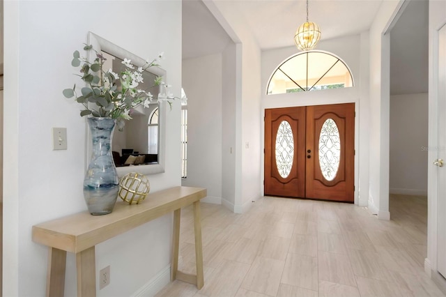 entrance foyer featuring a chandelier, baseboards, french doors, and a towering ceiling