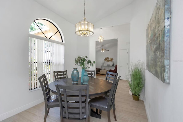 dining area featuring a chandelier, vaulted ceiling, baseboards, and a ceiling fan