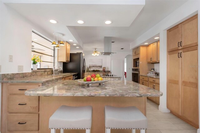 kitchen featuring stainless steel appliances, exhaust hood, light brown cabinets, a kitchen breakfast bar, and recessed lighting