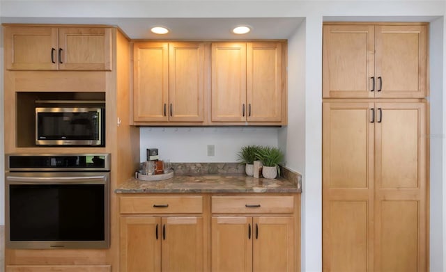 kitchen with appliances with stainless steel finishes, dark stone countertops, recessed lighting, and light brown cabinetry