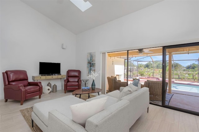living room with a sunroom, high vaulted ceiling, a skylight, and ceiling fan