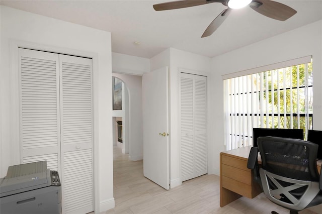 office featuring ceiling fan, baseboards, and arched walkways