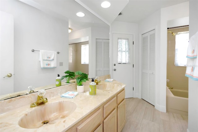 full bath featuring a closet, double vanity, and a tub to relax in