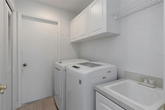 clothes washing area with cabinet space, washing machine and dryer, and light wood finished floors