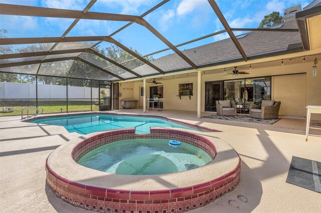 view of pool featuring a ceiling fan, a patio, glass enclosure, and a pool with connected hot tub