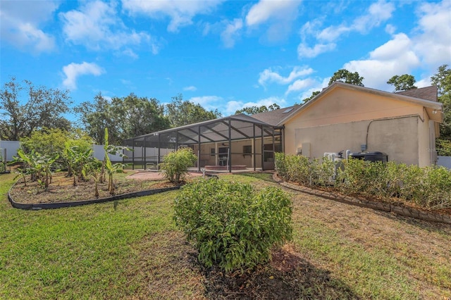 rear view of property with a lawn, glass enclosure, and stucco siding