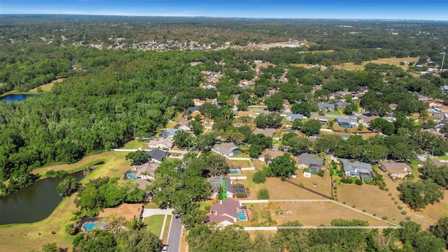 aerial view of residential area featuring a large body of water and a heavily wooded area