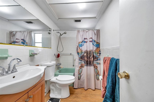 3621 Beacon Square Dr, Holiday, FL 34691 - full bath with tile walls, wood finished floors, toilet, vanity, and shower / bath combo with shower curtain
