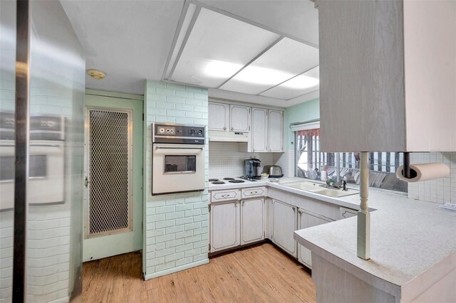 3621 Beacon Square Dr, Holiday, FL 34691 - kitchen featuring white appliances, a sink, light countertops, light wood-type flooring, and decorative backsplash