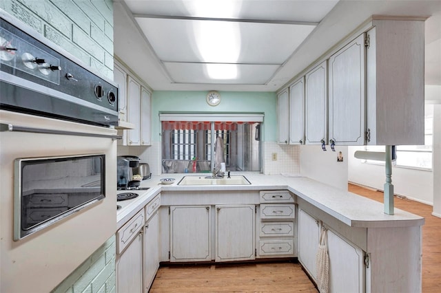 3621 Beacon Square Dr, Holiday, FL 34691 - kitchen with a sink, white oven, light countertops, backsplash, and a peninsula